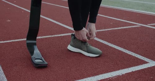Crop View of Disabled Male Person with Prosthetic Running Blades Tying Shoelaces and Standing at