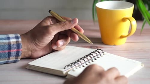 Close Up of Man Hand Writing on Notepad
