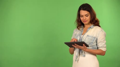 A Young Beautiful Caucasian Woman Works on a Tablet Then Smiles at the Camera Green Screen
