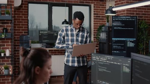 Smiling Coder Holding Open Laptop in Urban Office