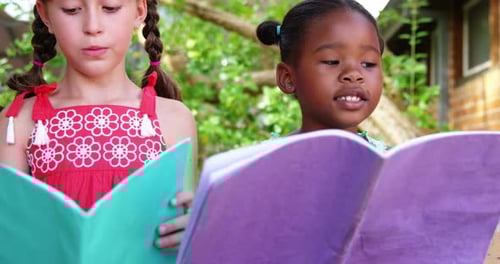 Schoolgirls reading book in campus at school