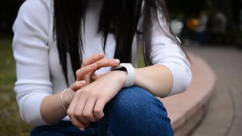 Woman Scrolls Smart Watch In Urban Environment