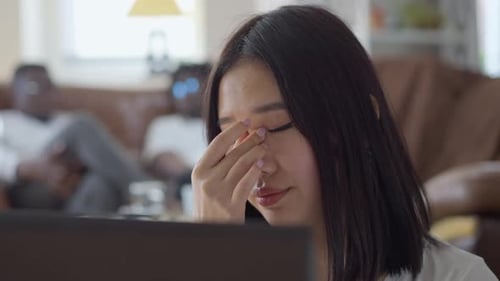 Closeup of Fatigued Beautiful Asian Young Woman Rubbing Eyes Messaging Online From Home Office