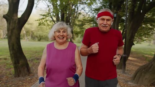 Active Senior Elderly Couple Doing Cardio Morning Exercise Workout. Man, Woman Running in City Park.