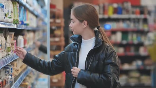 A Young Girl Chooses Dairy Products in the Store