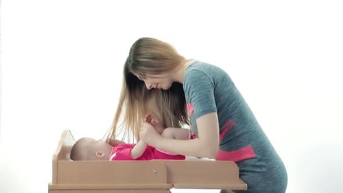 Caring Young Adult Woman with Baby on Changing Table