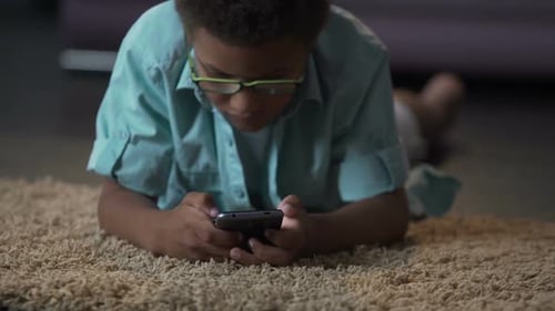 Boy Lying on Carpet Using Smartphone