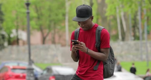 Young Man Using Mobile Phone in City Park