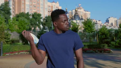 Young Adult Removes Face Mask in City Park