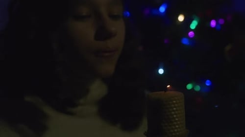 Girl Blowing Out Candlelight in Festive Holiday Scene
