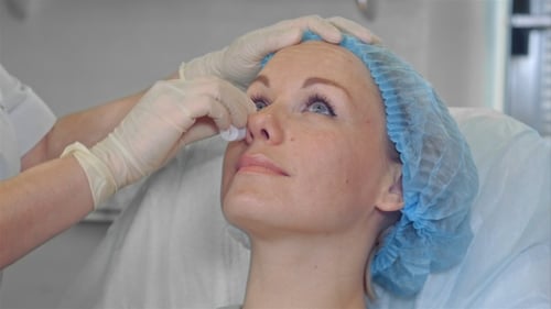 Cosmetologist Wipes Face of Woman in Hospital Bed