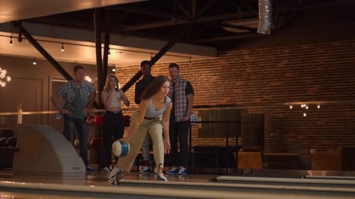 Eine kaukasische brünette Frau wirft eine Bowlingkugel und schlägt einen Schuss mit einem Wurf und Umarmungen aus und