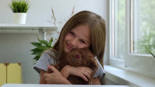 Smiling Child Hugging a Teddy Bear Indoors
