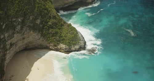 Close Up Slow Motion Shot of Blue Waves Crashing on the Tropical Rocky Cliffs and Sandy Beach Top
