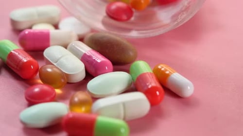 Close Up of Colorful Pills Spilling on Pink Background