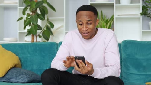 Man Celebrates Good News on Smartphone at Home