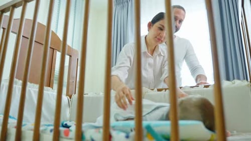 Loving Parents Watching Baby Sleep in Crib