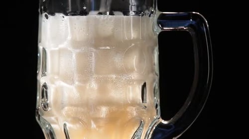 Beer Pouring into Glass Stein Overflowing