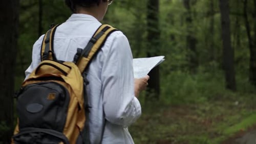 Person with Map Hiking Through Green Forest