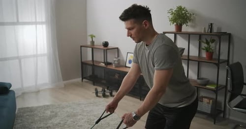 Strong Man Is Training with Sporty Rubber Tape in Apartment Home Fitness at Weekend Keeping Fit and