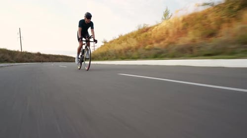 Young fit man cycling on road downhill