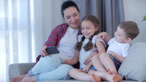 Woman and Children Looking at a Smartphone on Couch