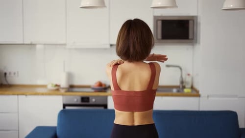 Woman Turn Her Arms Practicing Yoga at Home Rear View