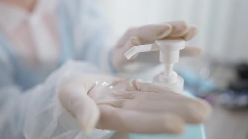 Gloved Hands Dispensing Hand Sanitizer and Rubbing Hands