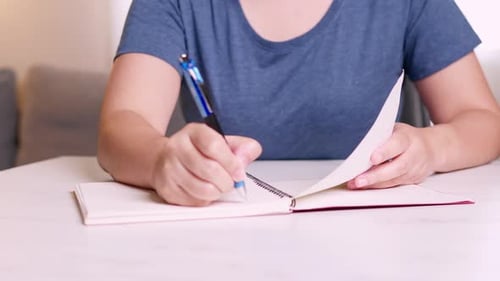 Close Up hands taking notes on a notebook about ideas for freelance designers.