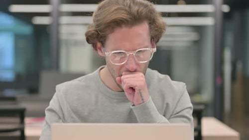 Adult Man Coughs While Working On Laptop