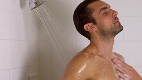 Man Taking Shower in Tiled Bathroom