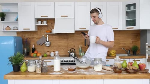 Young Adult Man Cooking in Kitchen With Phone