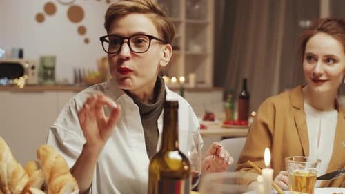 Jeune jolie femme donnant des toasts et des verres à tinter avec des amis au dîner