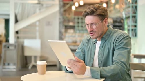 Disappointed Middle Aged Man Reacting to Loss on Tablet in Cafe