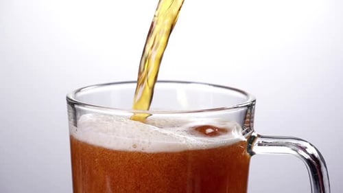 Golden Beverage Being Poured into a Glass Mug