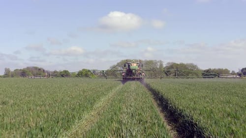 Tractor Sprays Crops in Green Agricultural Field