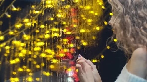 Woman Behind Glass with Christmas Lights at Night