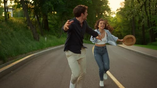 Happy Man and Woman Having Fun Outdoors. Happy Couple Running on Road in Park