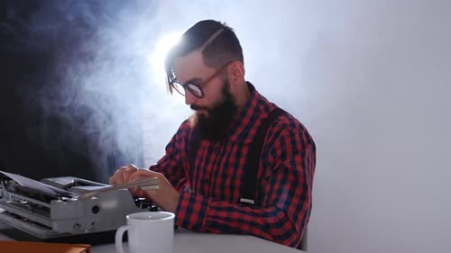Concepto del día del escritor. Joven escritor en un cuarto oscuro escribiendo en una máquina de escribir