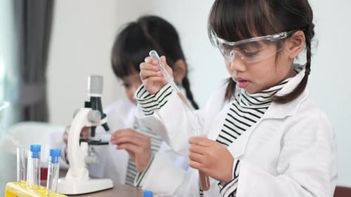 Girls Doing Science Experiment with Microscope and Test Tubes