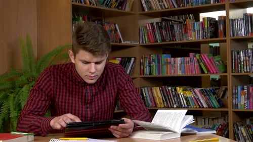 Student Using His Digital Tablet in a Library, Preparing for Abstracts. Close Up