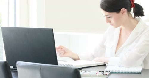 Woman Working at Desk with Laptop and Notebook