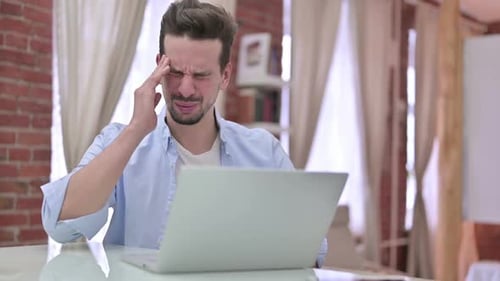 Man Typing on Laptop Has a Headache