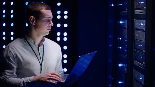IT Worker with Laptop in Futuristic Server Room