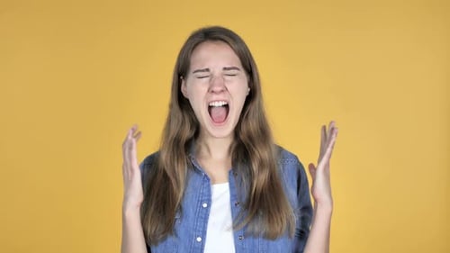 Woman Shouts and Celebrates Success on Yellow Backdrop