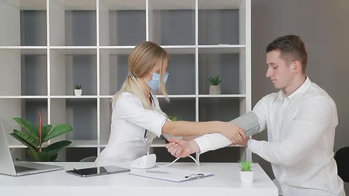 Blonde Female Doctor Checks Young Man's Blood Pressure