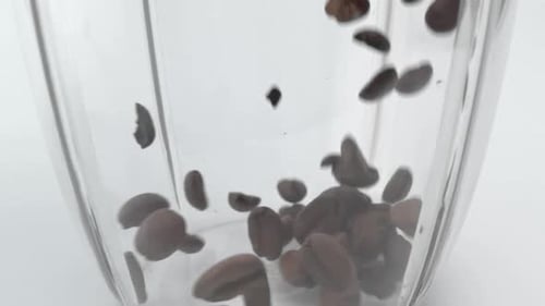 Coffee Beans Falling Into a Clear Glass Bowl