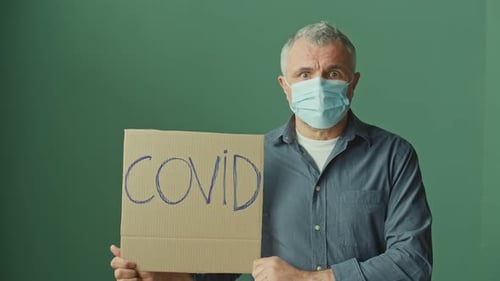 Man Holds Up COVID Cardboard Sign Wearing Mask