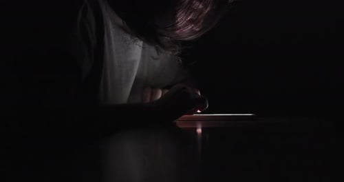 Frau benutzt Swiping Phone in völliger Dunkelheit. Repariert ihr Haar.