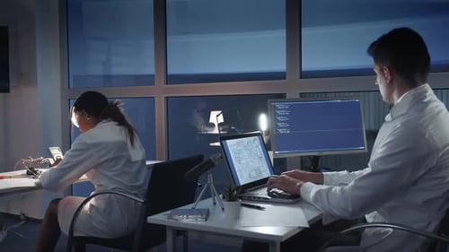 Team of Electronics Engineers in White Coats Working on the Computers in Advanced Laboratory